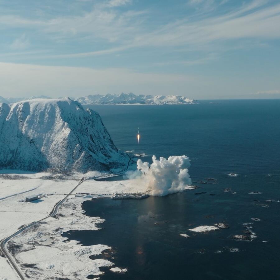 Aerial view of coastal launch site with plume